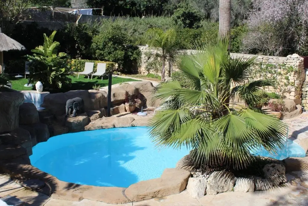 Outdoor pool surrounded by gardens
